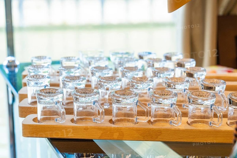 Several small glasses on a wooden tray in an elegant and well-lit room, Schifffahrt, Neckar, Wilhelma, Stuttgart, Germany