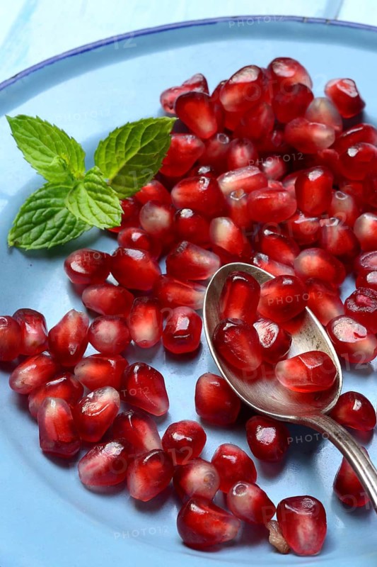 Pomegranate seeds and spoons on plate, Punica granatum
