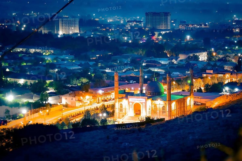 Osh central mosque kyrgyzstan timelapse day to night cityscape glowing green dome minarets urban lights residential district mountain backdrop dusk transition. Sulaiman - Too mountain