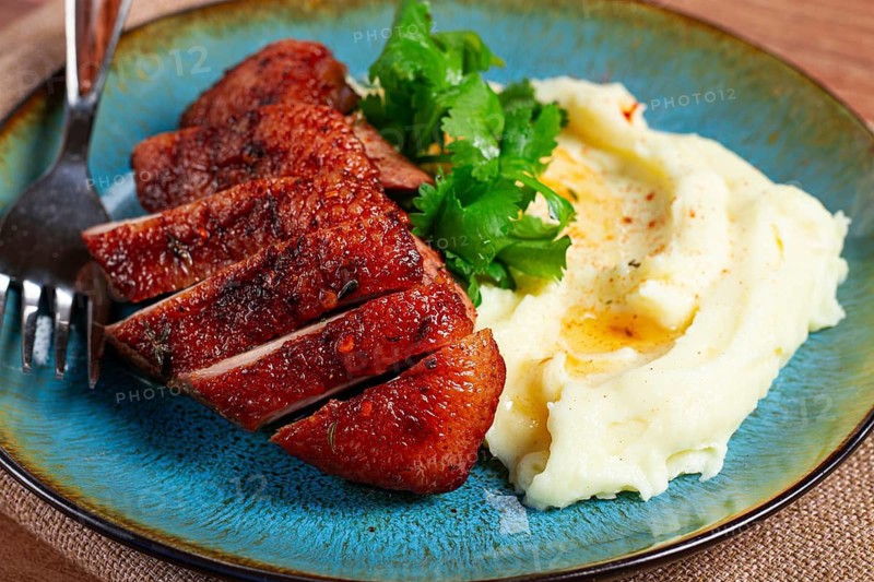 Roast duck breast, sliced with mashed potatoes, on a plate, close-up, no people