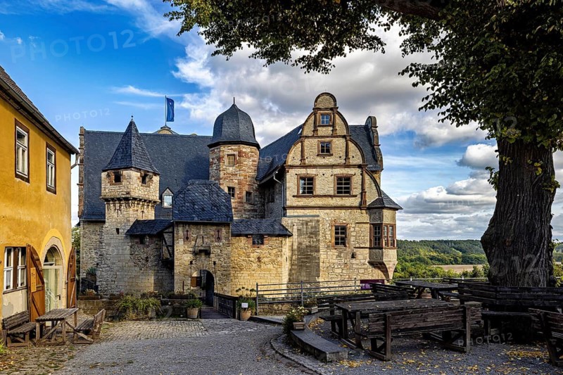 Picturesque view of an old castle with visible towers and a paved road in the foreground, The Upper Castle of Kranichfeld in Thuringia