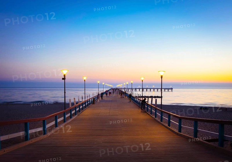 Illuminated romantic vintage Palanga pier after sunset with people walking in beautiful summer evening. Lithuania summer holiday landmarks destination. Palanga.Lithuania