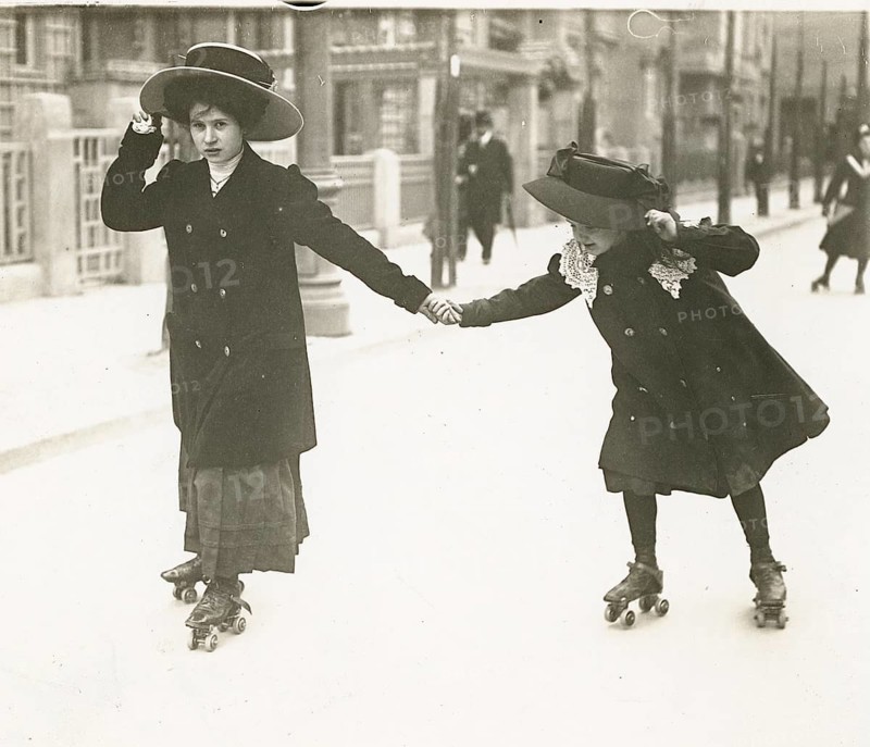 Berlin, ice-skating, middle class, children, street, practice, help, leisure, two girls with hats on rollerblades on a street in an early 20th century scene, Philipp Kester, around 1906