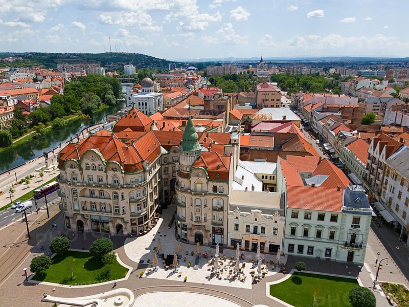Aerial view of buildings with red roofs and green tower in a hilly cityscape near a river, aerial view, Palace of the Black Eagle on the left, Piata Unirii, Unity Square, Oradea, Bihor district, Kreischland, Transylvania, Romania