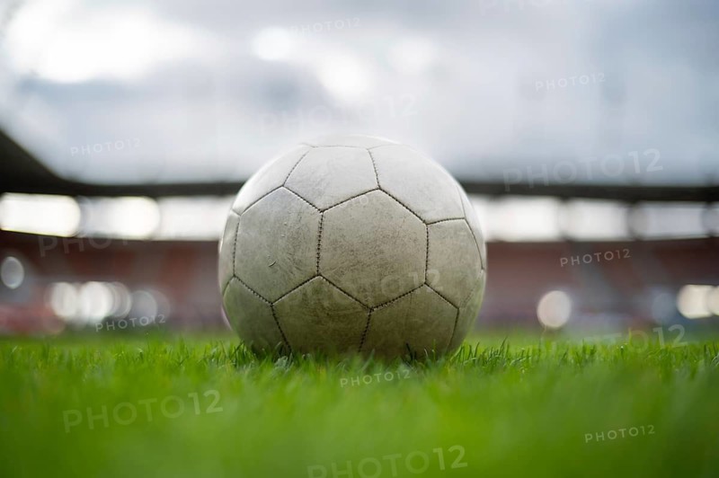 White soccer ball lying on the grass at stadium in Lubin, Poland