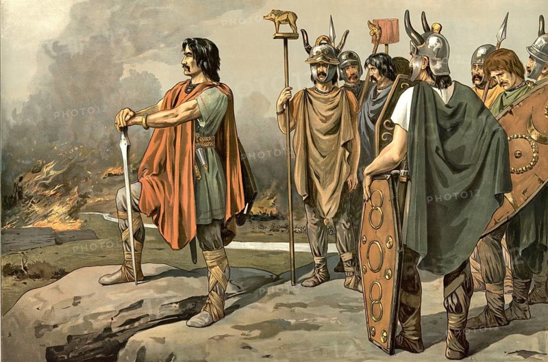 Vercingetorix, depicted as a Gaulish leader standing on a rock and looking at a burning battlefield, accompanied by other Gauls. Vercingetorix united the Gallic tribes in 52 BC to massively resist the Roman conquest. In order to deprive Caesar's troops of their food supply and supplies, he deliberately had Gallic villages, fields and supplies burned, school painting, illustration, reproduction from a model from the 19th century. School picture, mural, authentic, file restored for optimal use, exact date of original unknown, historical