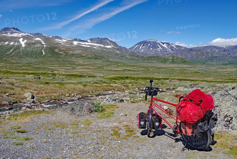 Loaded bike in front of a vast mountain landscape with blue sky and individual clouds, bicycle trip, Gjendersheim, Jotumheimen, Norway