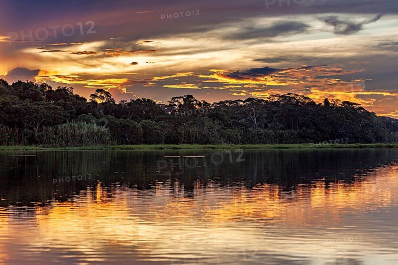 Atmospheric sunset with orange sky over a calm river, sunset on the Beni River near Rurrenabaque in the Amazon basin in Bolivia