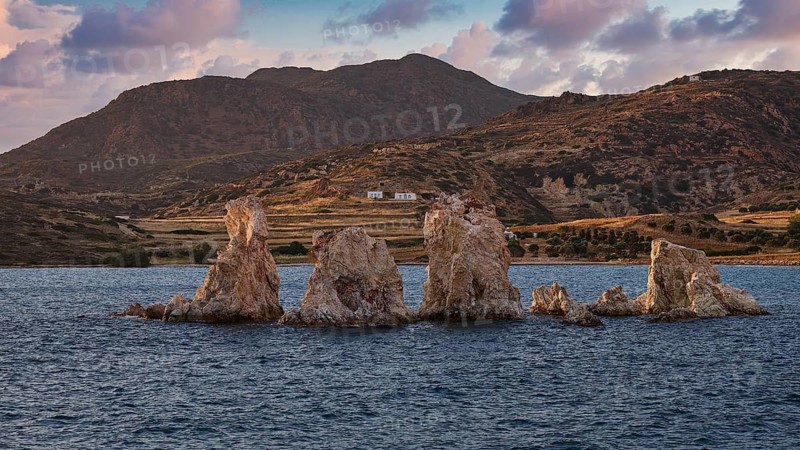 Rocks and blue waters with mountains in the background and clouds, Aspragremna, White Cliffs, Mavorspilia Beach, Kimolos Island, Kimolos, Cyclades, Greek Islands, Greece