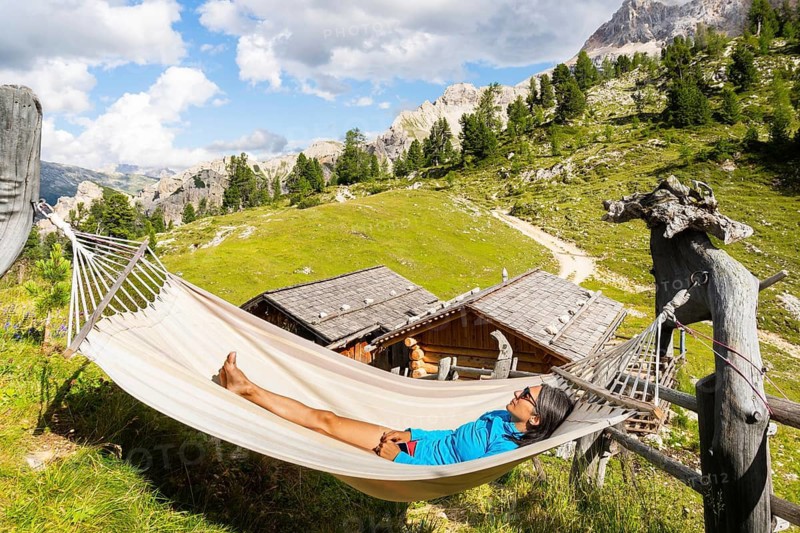 Female hiker resting in hammock at mountain hut on Tre Cime trail in Dolomites enjoying alpine scenery wellness adventure and hiking break
