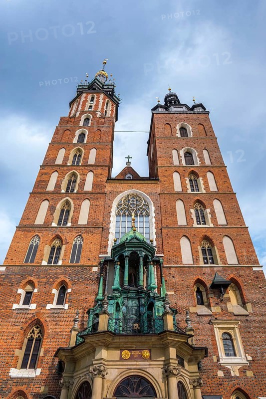 Low angle view of Saint Mary Basilica in Krakow, Poland, with red brick towers, Gothic church facade, blue sky, visible inscription, and no people