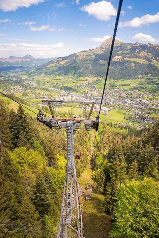 Cable car high above a wooded slope with views of a valley and mountains in the distance, Hahnenkamm, Kitzbühel, Austria