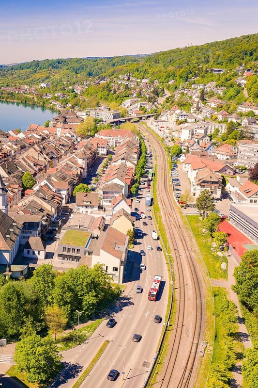 City view with tracks and adjacent buildings surrounded by green trees in summer, electrification of the Hochrheinbahn, conversion of the train station, Waldshut, Tiengen, Germany