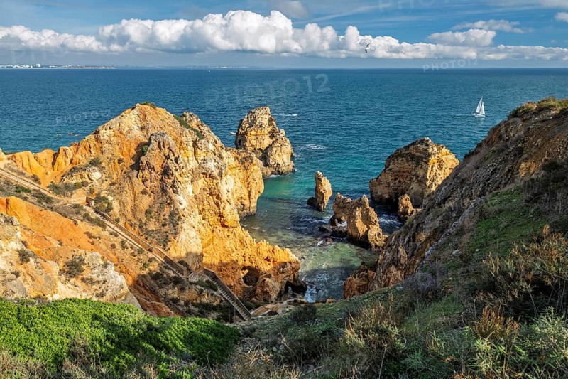 Scenic spectacular and Atlantic view of the Algarve coastline showing cliffs at Ponte da Piedade. A tourist yacht can be seen cruising around the scenic coastal pillars