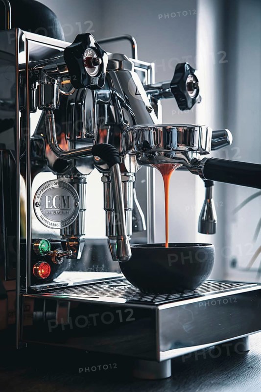 Professional preparation of espresso with a portafilter machine: The espresso flows from the portafilter into the espresso cups
