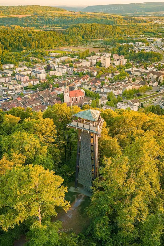 An observation tower rises above a thick forest with a city in the background, Tiengen, Waldshut, Tiengen, Germany