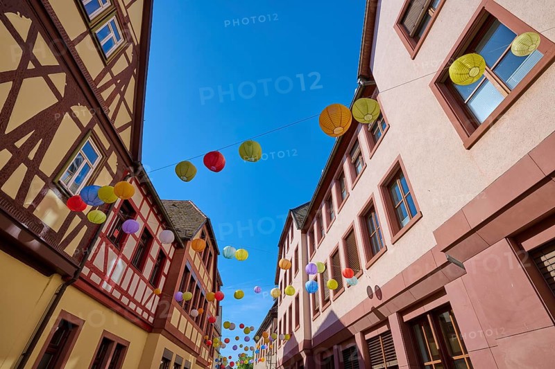 Colourful lanterns hang over a sunny road between half-timbered houses, Lohr am Main, Schneewittchenstadt, Main-Spessart district, Mainfranken, Lower Franconia, Bavaria, Germany