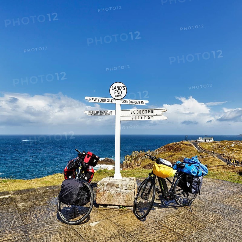 Two e-bikes by the sea, famous signpost to New York, John o' Groats, Scilly and Höxter Bödexen, bike tour, coastline near Land's End, Lands End, Penzance, Penwith Peninsula, Cornwall, England, Great Britain