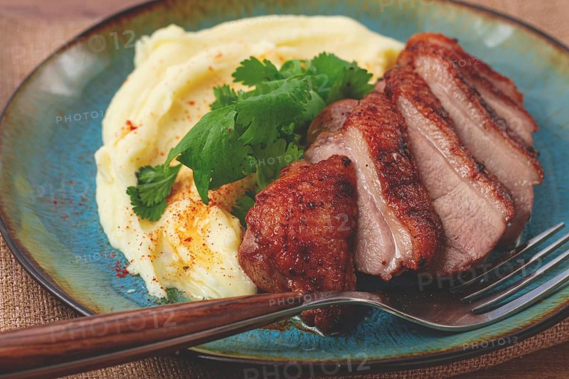Roast duck breast, sliced with mashed potatoes, on a plate, close-up, no people