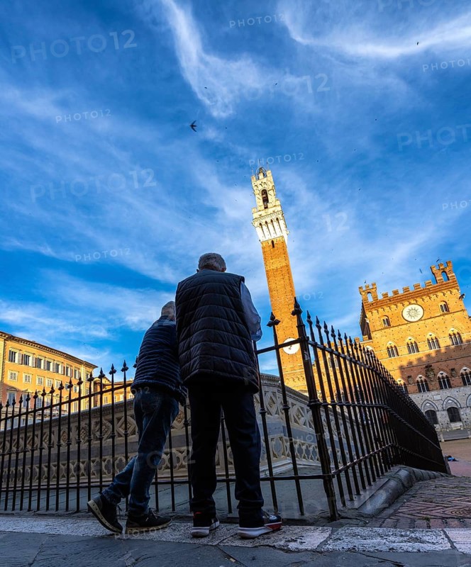 Seniors at Piazza del Campo look at Palazzo Pubblico, Siena, Tuscany, Italy