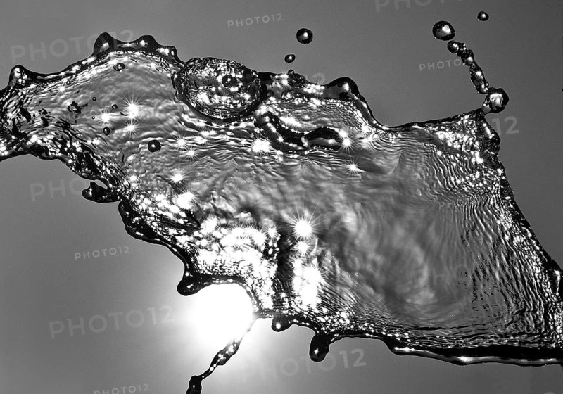 Water frozen by short exposure moving in backlight in front of the sun