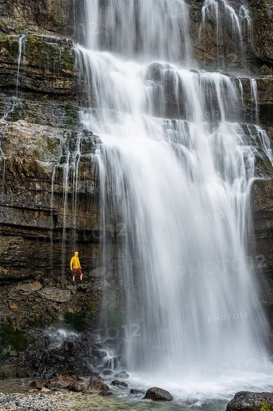 Adventure, Little hiker under large Cascata di Mezzo waterfall, long exposure, Vallesinella, Brenta, Trentino, Italy