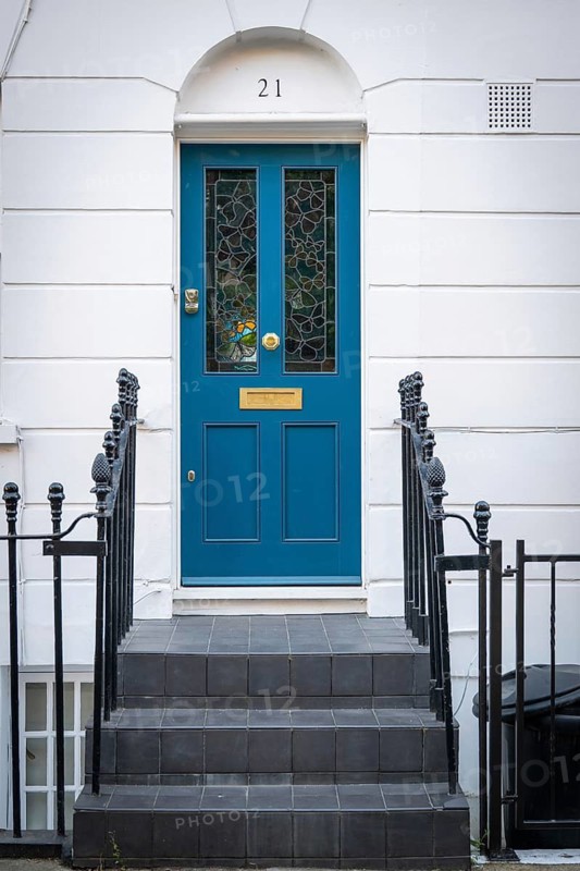 Blue front door with gold fittings and stained glass panes in white house facade surrounded by black metal railing, Borough of Chelsea and Kensington, London, England, Great Britain, Great Britain