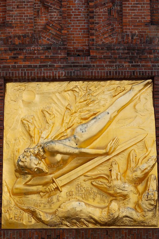 The gilded façade relief The Light Bringer by sculptor Bernhard Hötger, historic Böttcherstraße in the old town of the Hanseatic City of Bremen from the 1920s, example of clinker expressionist architecture, brick architecture, popular tourist destination, sword, three-headed snake or dragon being, Germany