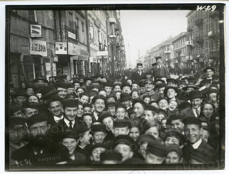 Jews, boys with caps, Poland, Jewish, Shtetl, Krakow, A large crowd of people smiling happily, standing close together on an urban street, some people assembled in, 1916