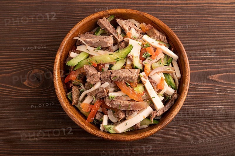 Meat salad with beef and vegetables in wooden bowl on brown wooden background. top view, flat lay, close up