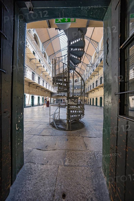 Narrow view of a spiral staircase in a bright prison corridor with old-fashioned design, Kilmainham Gaol Prison, Dublin, Ireland