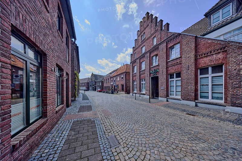 Historic city center, historic brick buildings, residential buildings and commercial buildings, façade with windows, staggered gable, street, paving stones, diffuse light, blue sky, cumulus clouds, Feldstraße, Wachtendonk, Kleve district, North Rhine-Westphalia, Germany