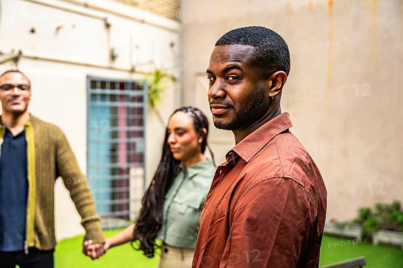Group of diverse individuals standing together, holding hands in a circle, finding mutual support and building community during a therapy session in a relaxed outdoor setting