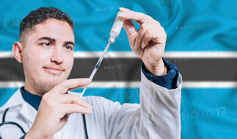 Doctor holding syringe on Botswana flag background. Medical professional holding syringe with Botswanan flag in the background