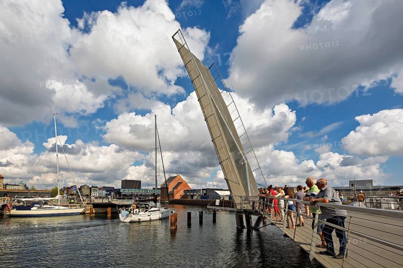 Klappbrücke über einem Hafen unter einem bewölkten Himmel mit Menschen, die auf einer Brücke stehen, Kopenhagen, Dänemark