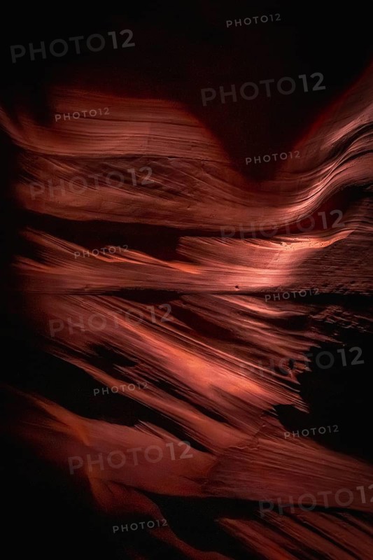 Antelope canyon's curving sandstone slot canyon walls creating flowing abstract patterns, sculpted by millions of years of water and wind erosion, illuminated by shafts of natural sunlight