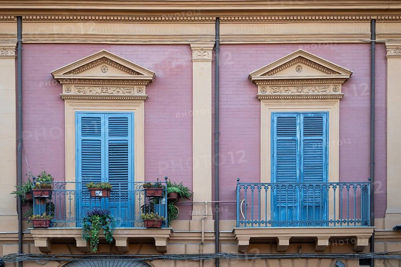 View of a purple neoclassical façade with two blue-painted balconies and shutters, Palermo, Sicily, Italy