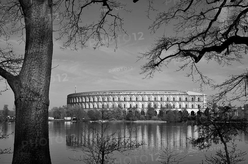 General view of the former, unfinished NSDAP Congress Hall, 1933–1945, with the Dutzenteich pond and lime trees (Tilia platyphyllos) in the foreground, Documentation Centre, Nazi Party Rally Grounds, black and white, Bayernstraße 110, Nuremberg, Middle Franconia, Bavaria, Germany