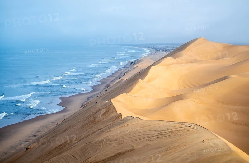Sand dunes and sea in morning light, view of the Atlantic coast from high sand dunes, Sandwich Harbour, Namib Naukluft Park, Namib Desert, Namibia