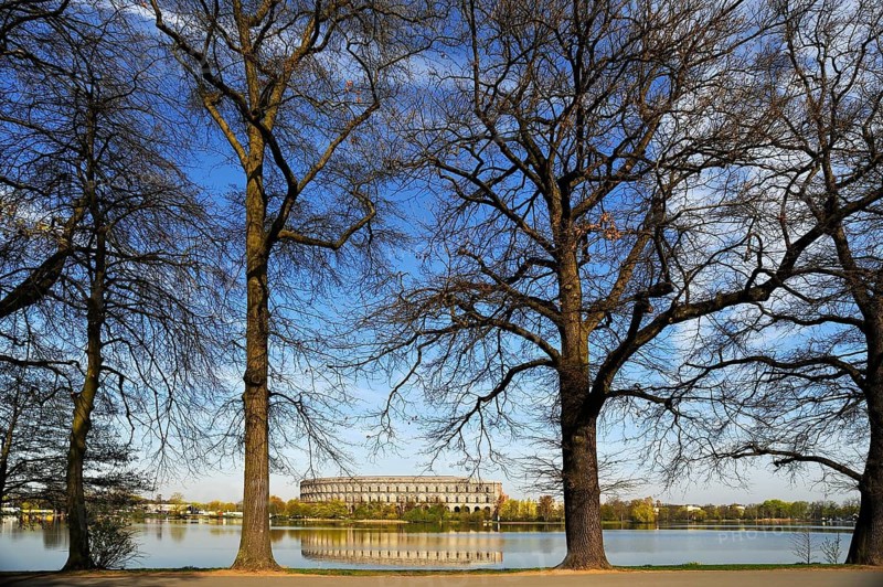 A general view of the former, unfinished NSDAP Congress Hall, 1933–1945, with the Dutzenteich and lime trees (Tilia platyphyllos) in the foreground, Documentation Centre, Reich Party Rally Grounds, Bayernstraße 110, Nuremberg, Middle Franconia, Bavaria, Germany