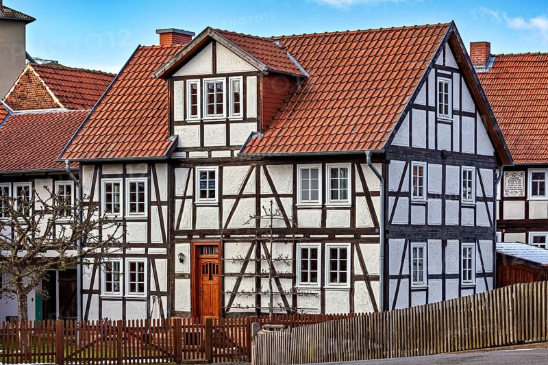 Traditional half-timbered house with red tiled roof and wooden fence against a clear sky, historic half-timbered house in Herleshausen in Hesse