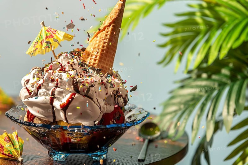 Sprinkles fall on sundaes decorated with cream, ice cream cone, umbrella and chocolate