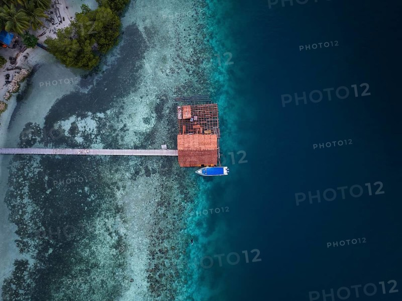Aerial view from top to bottom of a jetty and a boat and a presented reef, Raja Ampat, West Papua, Indonesia