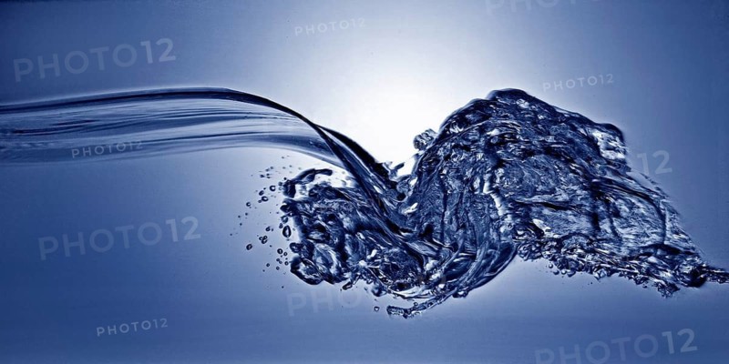 A small longitudinal wave frozen by short exposure in crystal-clear water in the photo studio in blue duplex toning