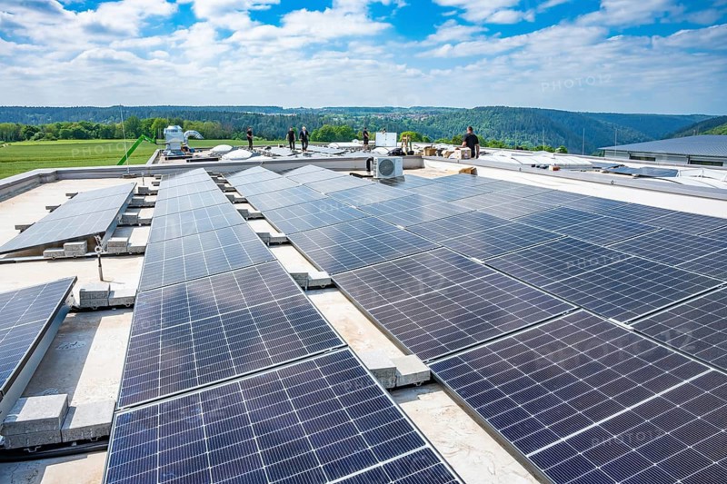 Large solar system on a roof under sunny sky, green surroundings, PV installation, Perrot company, Calw, Germany