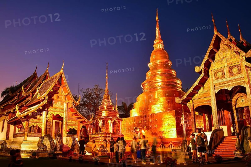 Chiang Mai, Thailand - 4th february, 2025: tourist by Wat Phra Singh Woramahawihan.Tourists visiting the golden chedi and Lanna - style temple buildings illuminated sunset twilight blue hour