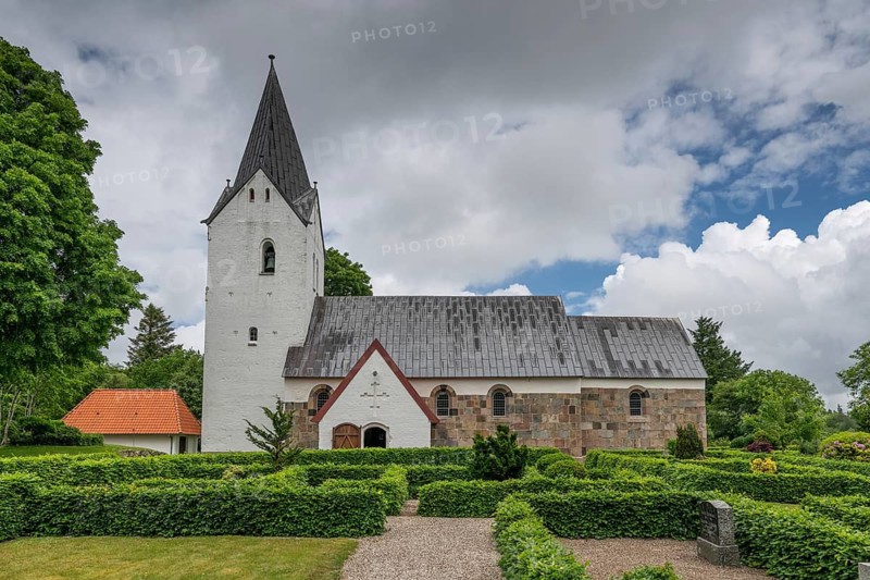 Well-maintained cemetery with low hedges, side view of an old Romanesque stone church, Husby Kirke, Holstebro Municipality, Denmark