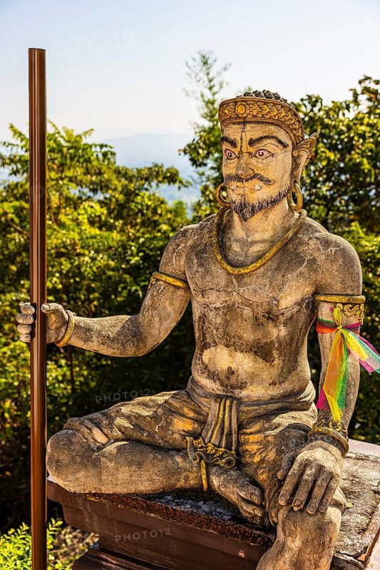 Stone statue of a seated temple guard in the Wat Phra That Don Phra Chan Buddhist temple, near Lampang, Lampang province, Thailand