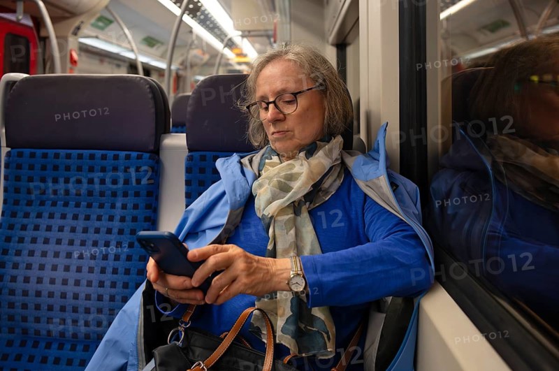 Interior view, elderly woman, glasses, sitting in S-Bahn, subway, train, typing on smartphone, cell phone, evening, night, night shot, public transport, Stuttgart, Baden-Württemberg, Germany