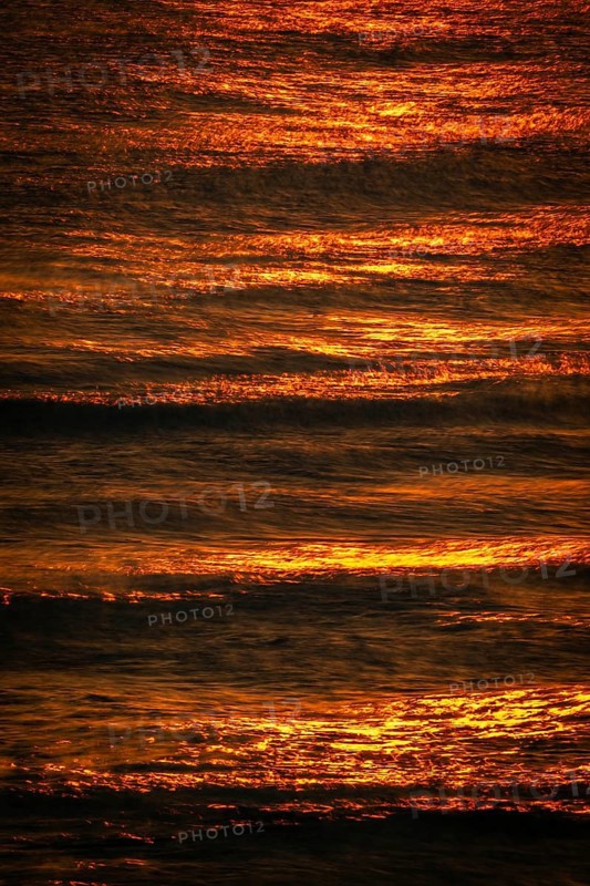 Setting sun bathes the sea and small waves in golden light, long exposure, Houvig Beach, North Sea, Denmark